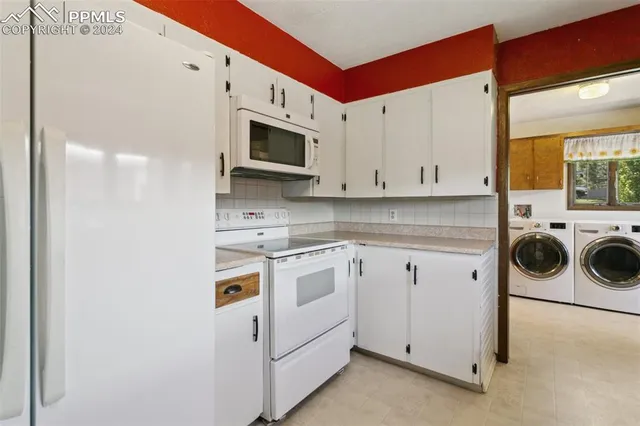 a view of a kitchen with white cabinets and white appliances