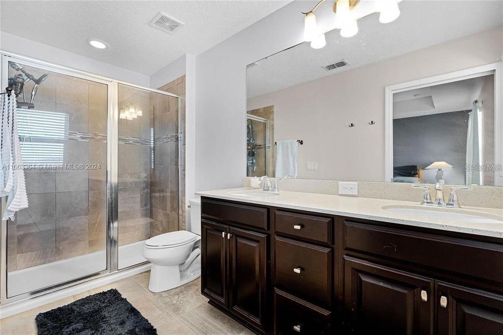 11819 Vermillion Avenue Windermere, FL 34786 - Photo 19 of 25 a bathroom with a double vanity sink toilet and shower