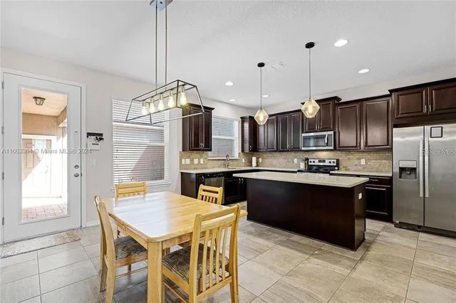 a kitchen with stainless steel appliances granite countertop a sink a stove a refrigerator a kitchen island with a dining table and chairs