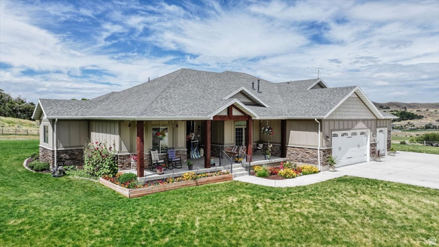 3123 East Riverdale Road Preston, ID 83263 - Photo 46 of 52 Ranch-style residence featuring a covered front porch with timber columns, a stone and siding exterior, an attached multi-car garage, and a concrete driveway
