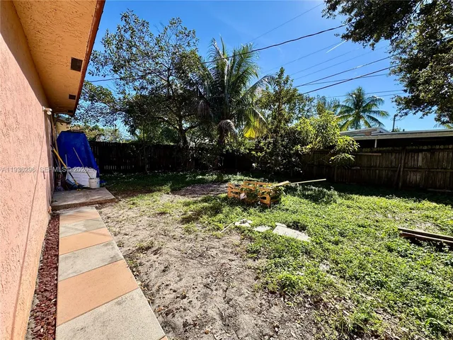 a view of backyard with potted plants and wooden fence