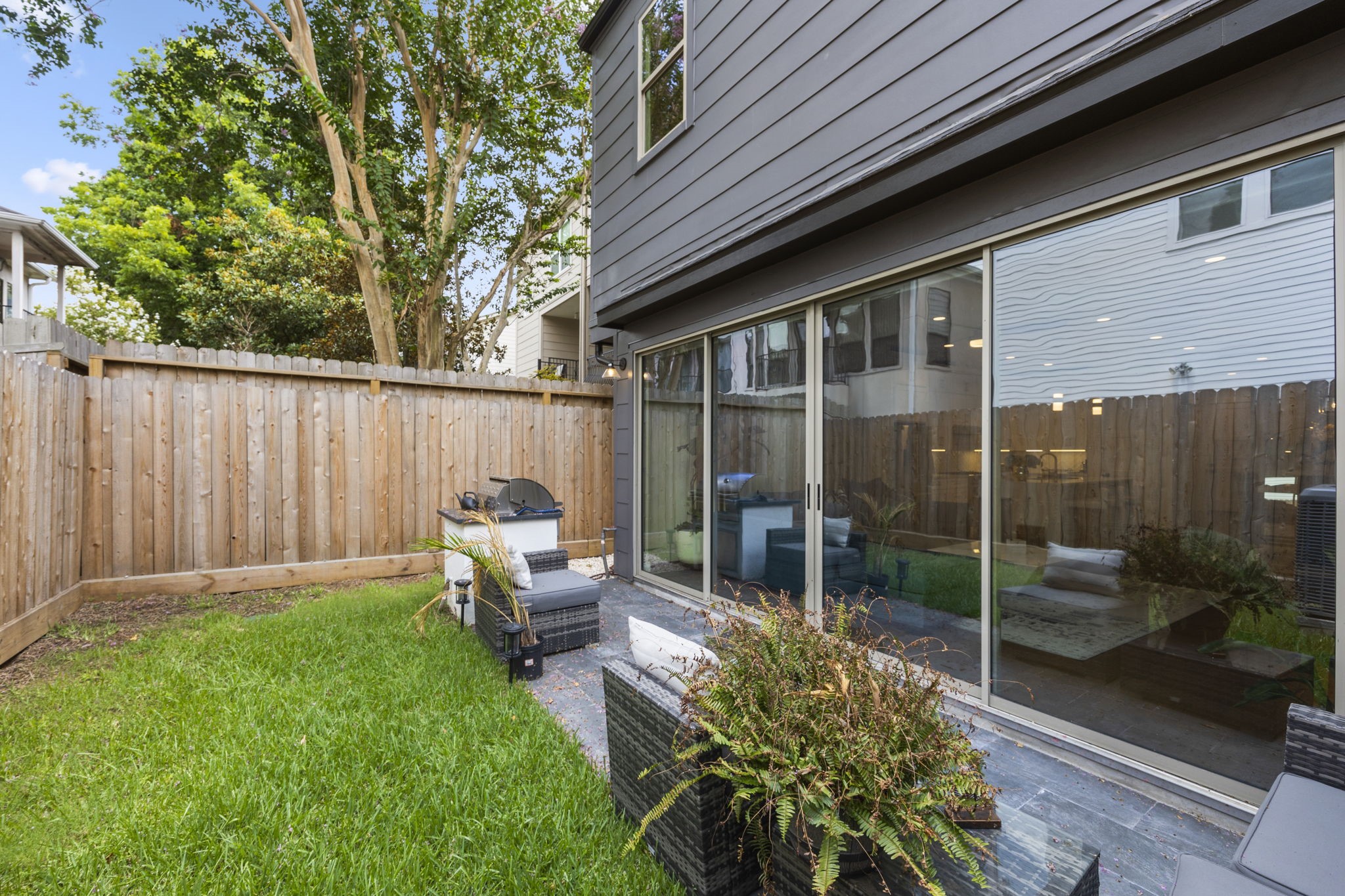 2411 Hazard Street Houston, TX 77019 - Photo 45 of 46 Additional view of the backyard highlights the spacious patio area and lush green space, perfect for outdoor activities and entertaining. The privacy fence adds seclusion, while large sliding doors connect the interior living space seamlessly to the outdoors, enhancing the indoor-outdoor flow.