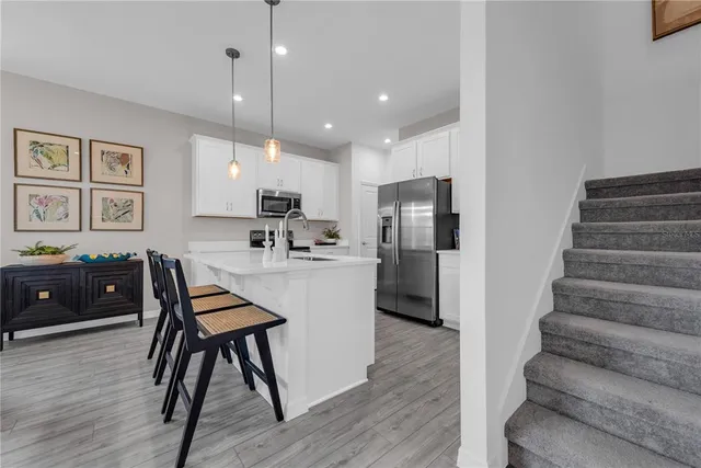 a kitchen with stainless steel appliances granite countertop a refrigerator a stove a sink dishwasher and a dining table with wooden floor