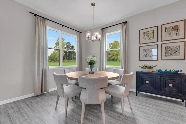a dining room with wooden floor a chandelier a wooden table and chairs