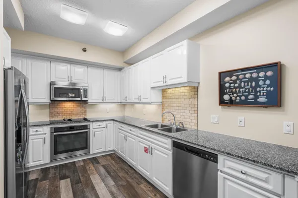 a white kitchen with granite countertop stainless steel appliances