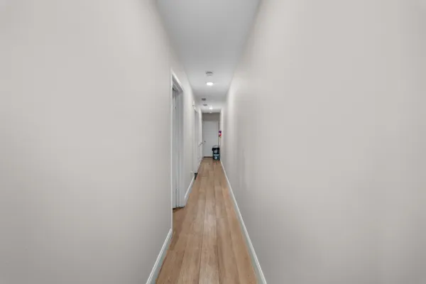 a view of a hallway with wooden floor and a bathroom