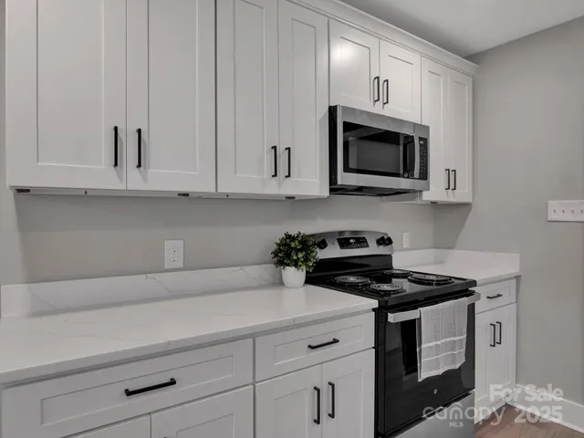 a kitchen with white cabinets and black appliances