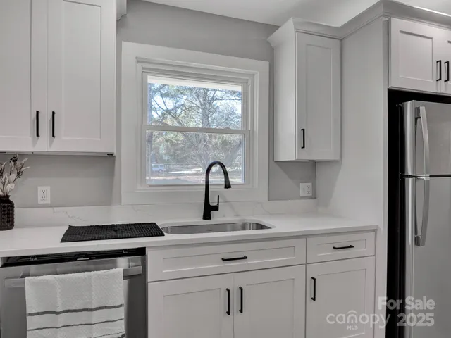 a kitchen with white cabinets and a window
