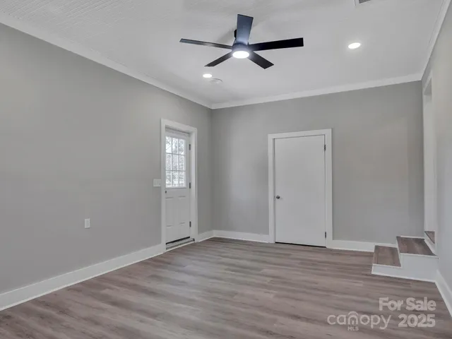 a view of an empty room with window and wooden floor
