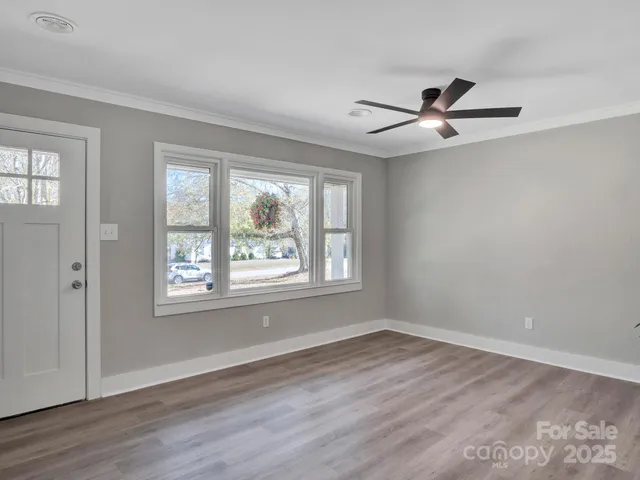a view of empty room with wooden floor and fan