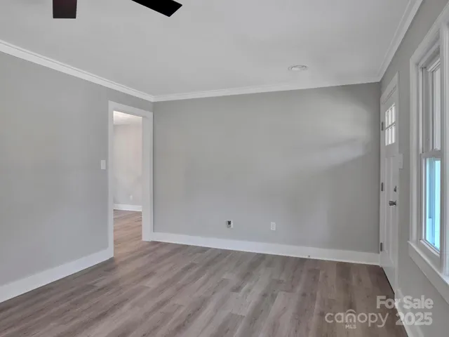 a view of an empty room with wooden floor and a window