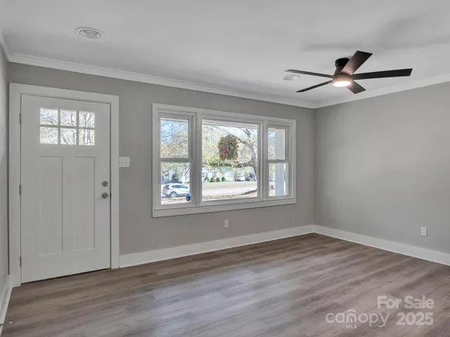a view of an empty room with wooden floor and a window