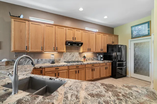 a kitchen with granite countertop a stove a sink and a refrigerator