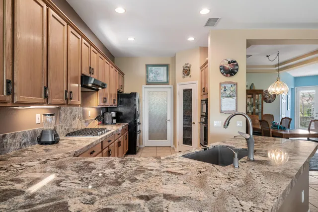 a kitchen with stainless steel appliances granite countertop a refrigerator and a stove top oven