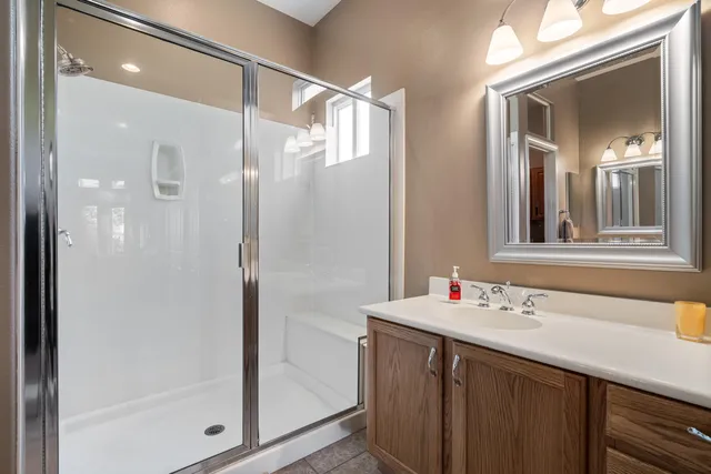 a bathroom with a granite countertop sink a toilet a mirror a vanity and shower