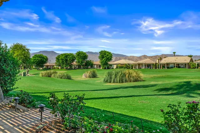 a view of a house with a big yard and palm trees