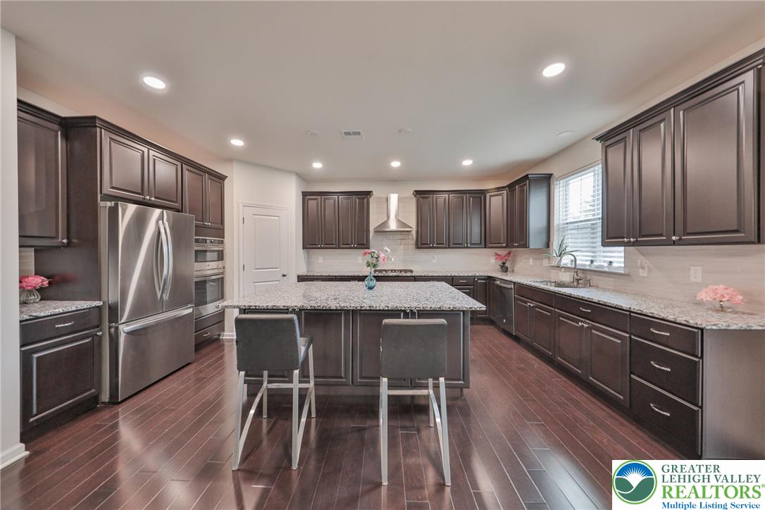338 Abby Road Macungie, PA 18062 - Photo 18 of 40 a kitchen with stainless steel appliances granite countertop a refrigerator a sink dishwasher a dining table and chairs with wooden floor