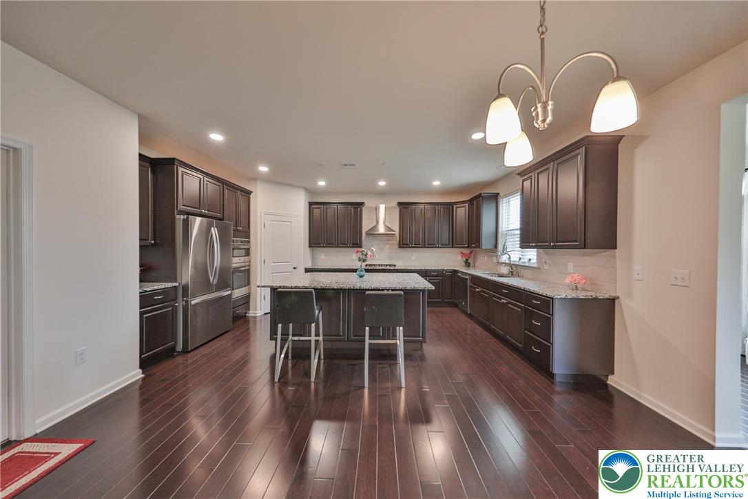 338 Abby Road Macungie, PA 18062 - Photo 10 of 40 a kitchen with stainless steel appliances kitchen island granite countertop wooden floors and view of living room
