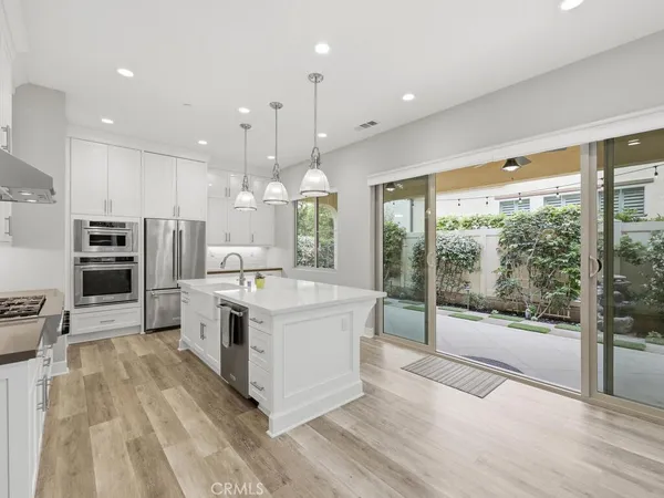 a large kitchen with stainless steel appliances kitchen island a large counter top and a wooden floors