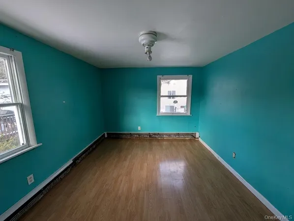 a view of an empty room with window and wooden floor