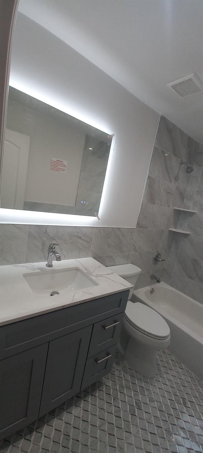 3 Hampton Road Lynbrook, NY 11563 - Photo 4 of 23 Bathroom with bathtub / shower combination, vanity, visible vents, toilet, and tile walls