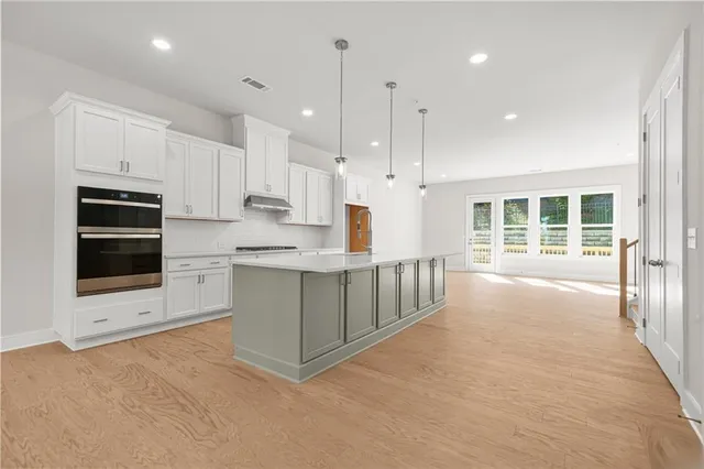 a kitchen with stainless steel appliances kitchen island granite countertop a stove a sink and white cabinets