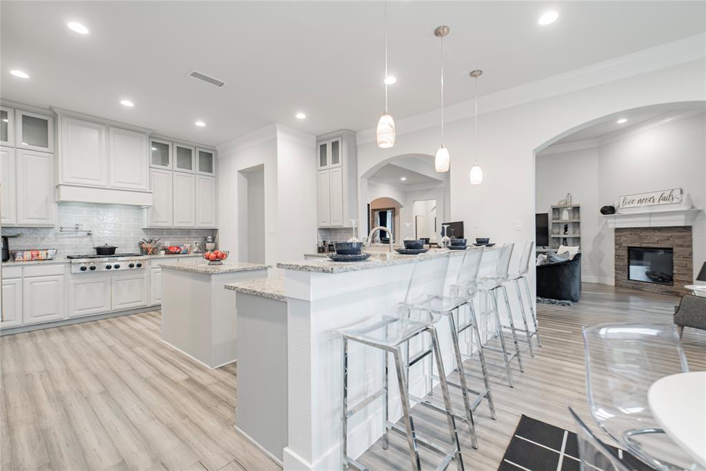 a kitchen with stainless steel appliances kitchen island granite countertop a stove a sink a refrigerator and a dining table with wooden floor