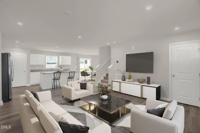 a living room with furniture a flat screen tv and kitchen view