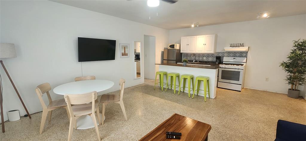 7725 Harding Avenue, Unit 4 Miami Beach, FL 33141 - Photo 3 of 6 a kitchen with stainless steel appliances granite countertop a stove a sink a microwave a dining table and chairs