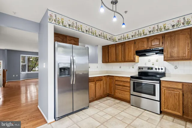 a kitchen with stainless steel appliances granite countertop a refrigerator a sink and a stove