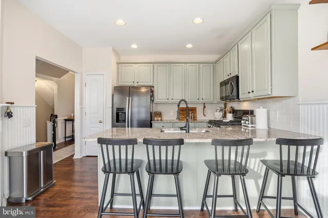 a kitchen with stainless steel appliances granite countertop a stove a refrigerator a kitchen island with a dining table and chairs