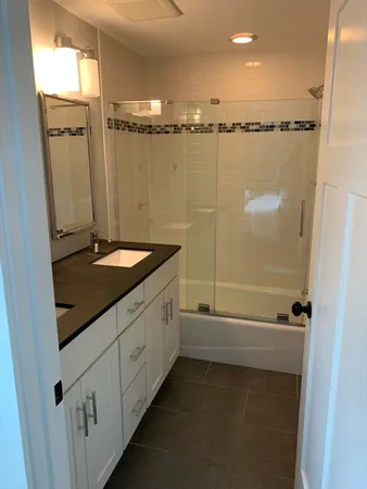 a bathroom with a granite countertop sink and a shower