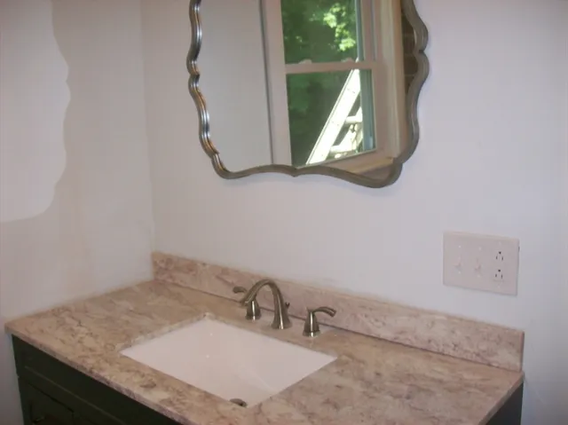 a bathroom with a granite countertop sink and a mirror