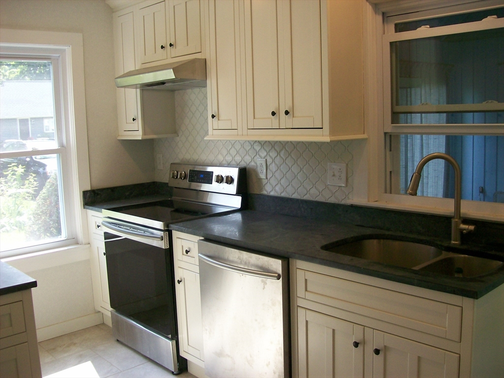 480 Pleasant Street Leicester, MA 01524 - Photo 4 of 17 a kitchen with granite countertop white cabinets and black appliances
