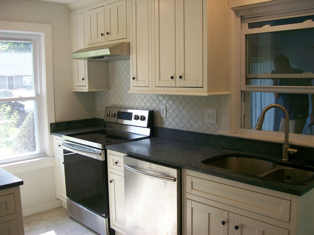480 Pleasant Street Leicester, MA 01524 - Photo 5 of 17 a kitchen with granite countertop white cabinets and black appliances