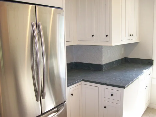 a kitchen with white cabinets and a refrigerator
