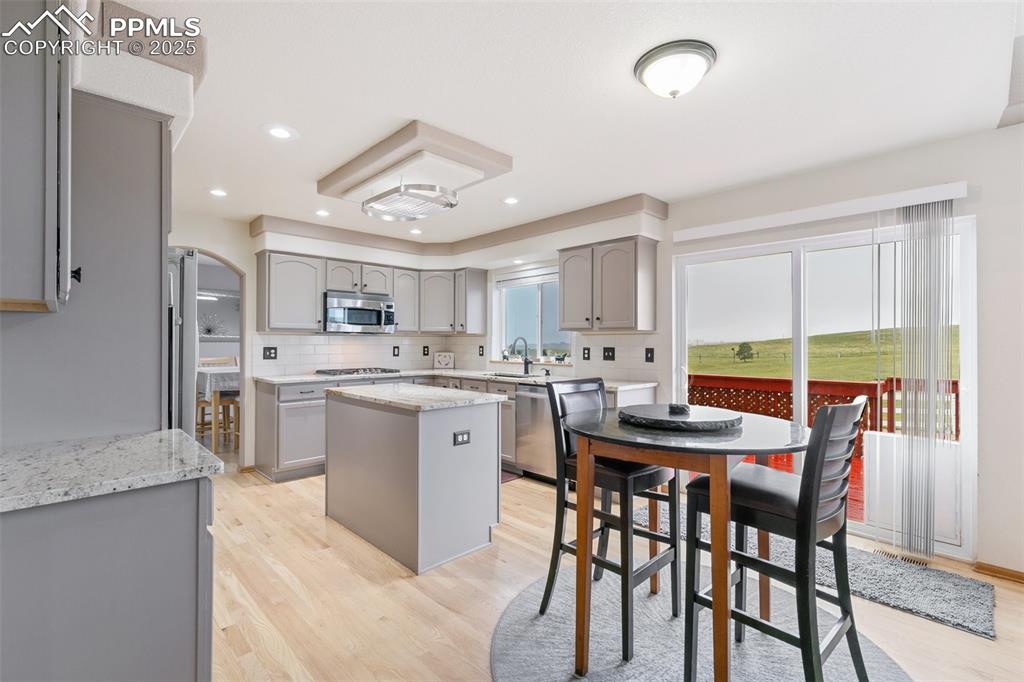 11960 Conestoga Trail South Elbert, CO 80106 - Photo 16 of 49 a kitchen with stainless steel appliances kitchen island granite countertop a table chairs sink and cabinets