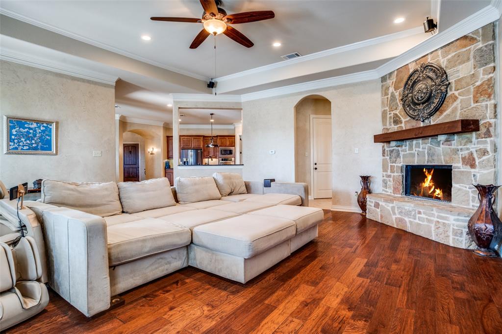 1929 Canyon Road Celina, TX 75009 - Photo 4 of 39 Living room featuring a ceiling fan, arched walkways, a fireplace, crown molding, and dark wood finished floors