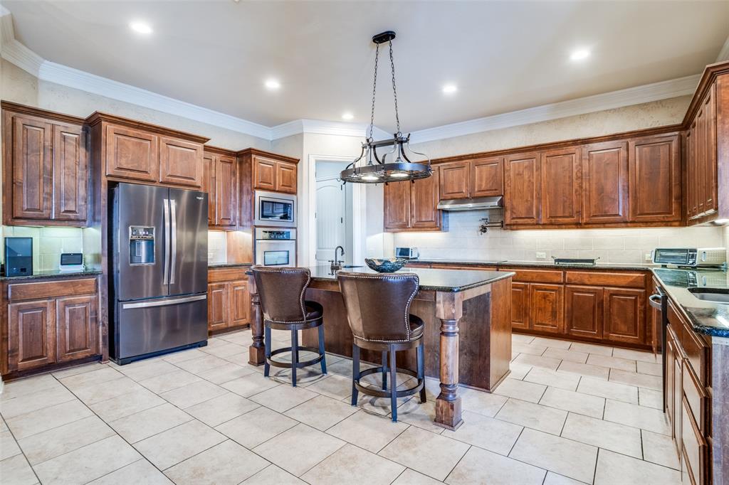 1929 Canyon Road Celina, TX 75009 - Photo 7 of 39 Kitchen featuring a kitchen bar, stainless steel appliances, a center island with sink, backsplash, and wood finish cabinets