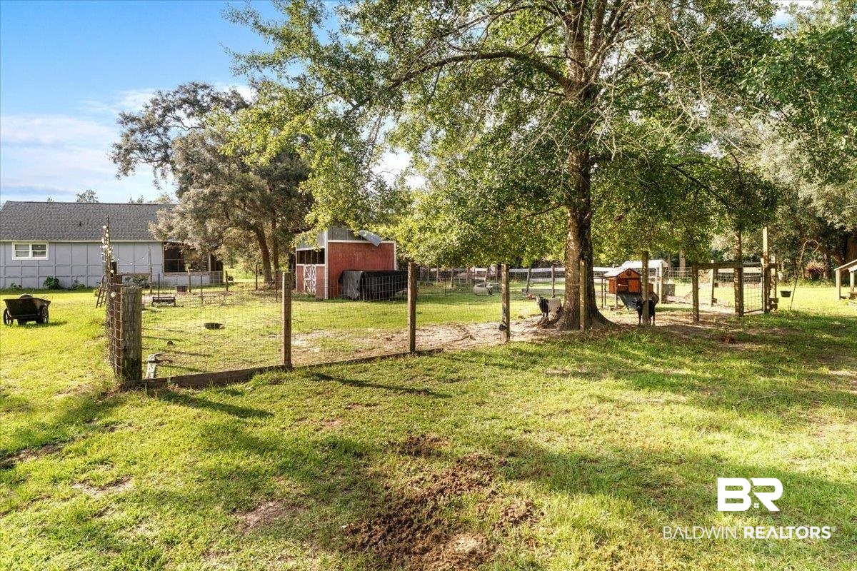 21011 River Road Robertsdale, AL 36567 - Photo 21 of 29 Expansive outdoor space featuring a fenced enclosure, mature trees, and a red barn structure
