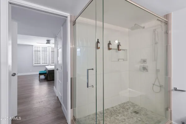 a view of a hallway with wooden floor and a bathroom