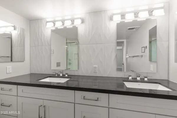 a bathroom with double vanity sinks and a mirror