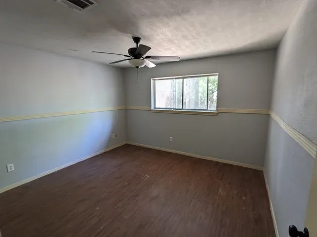 an empty room with a window and a ceiling fan