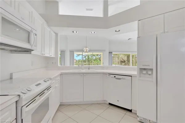 a kitchen with white cabinets and window