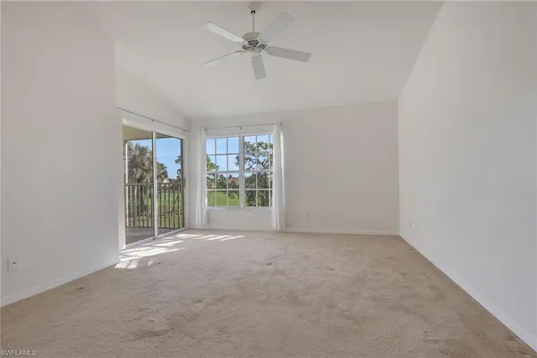 an empty room with windows and ceiling fan