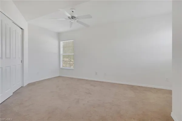 an empty room with a ceiling fan and a window