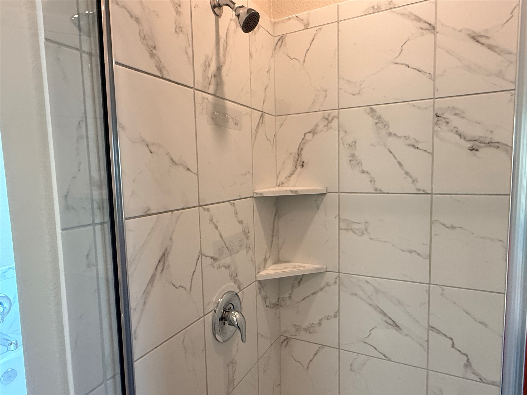 129 Perfect World Loop Jarrell, TX 76537 - Photo 18 of 31 A pristine shower stall featuring elegant tile work and integrated shelving for convenience.