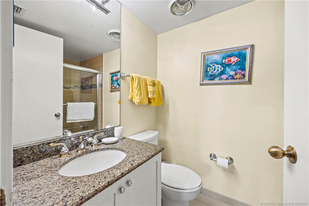 669 Northeast Plantation Road, Unit 405 Stuart, FL 34996 - Photo 30 of 34 a bathroom with a granite countertop sink mirror vanity and toilet
