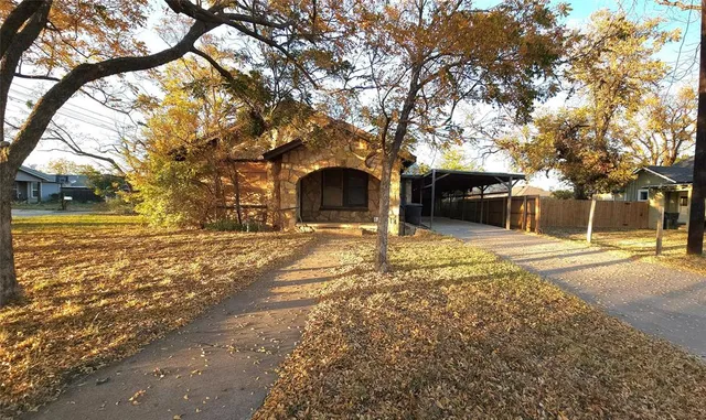 a front view of a house with a yard covered with trees