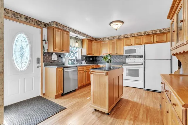 a kitchen with granite countertop a refrigerator a stove a sink and white cabinets with wooden floor